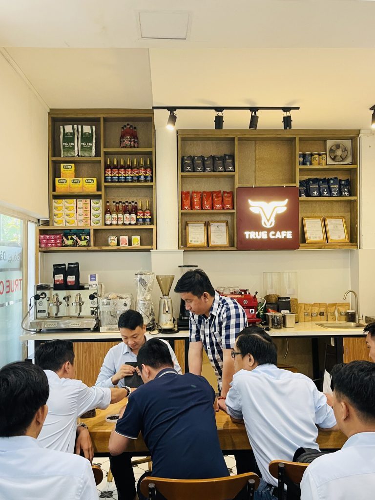 Học viên đứng quanh quầy bar True Cafe xem thao tác pha chế trên máy espresso