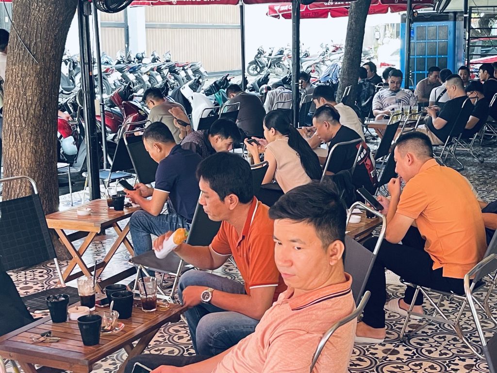Khách ngồi kín bàn gỗ tại quán cà phê vỉa hè dùng cà phê True Cafe