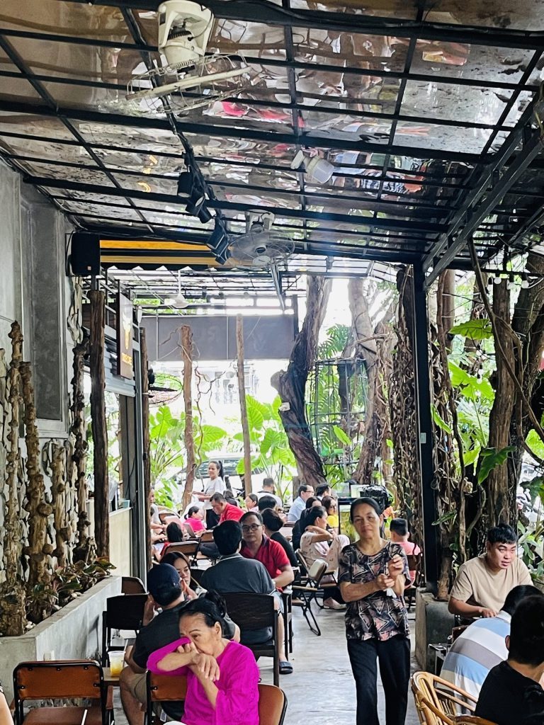 Khu ngồi dọc hành lang phủ cây xanh của quán cà phê dùng cà phê True Cafe