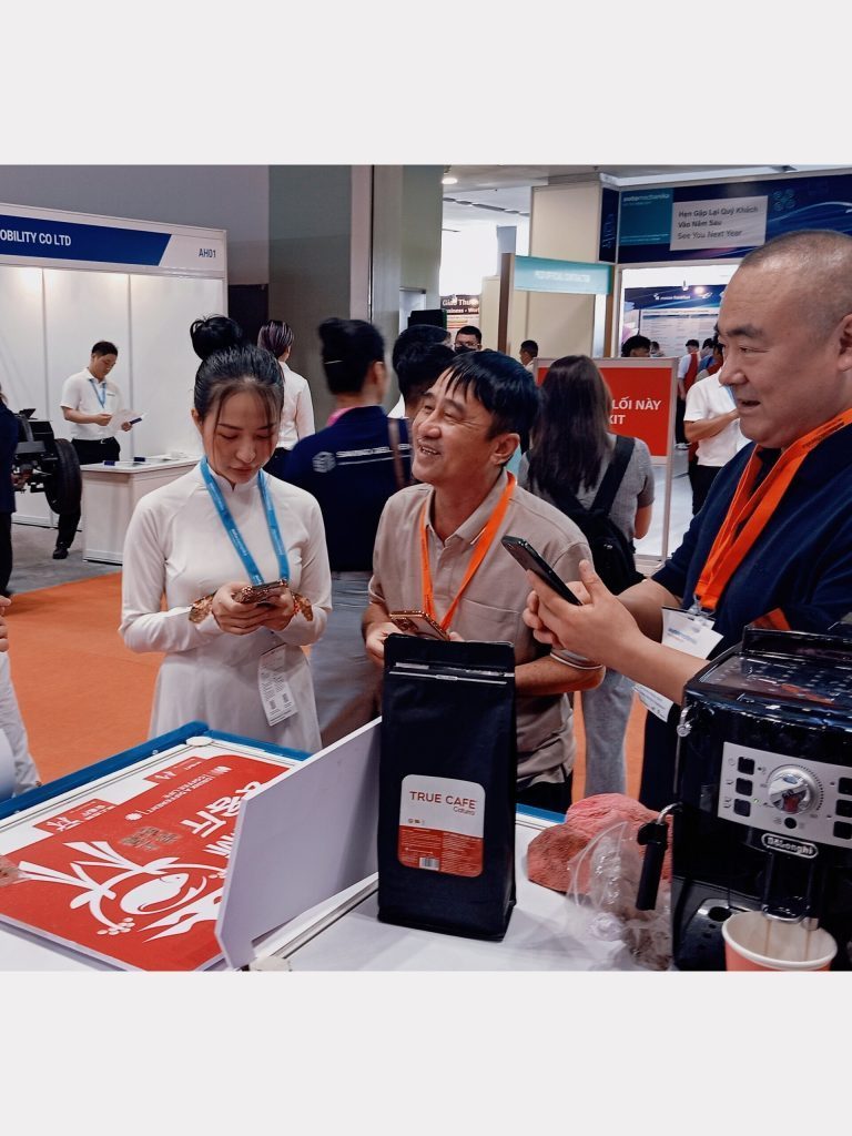 Nhân sự True Cafe giới thiệu túi cà phê rang mộc và máy pha cho khách tại hội chợ
