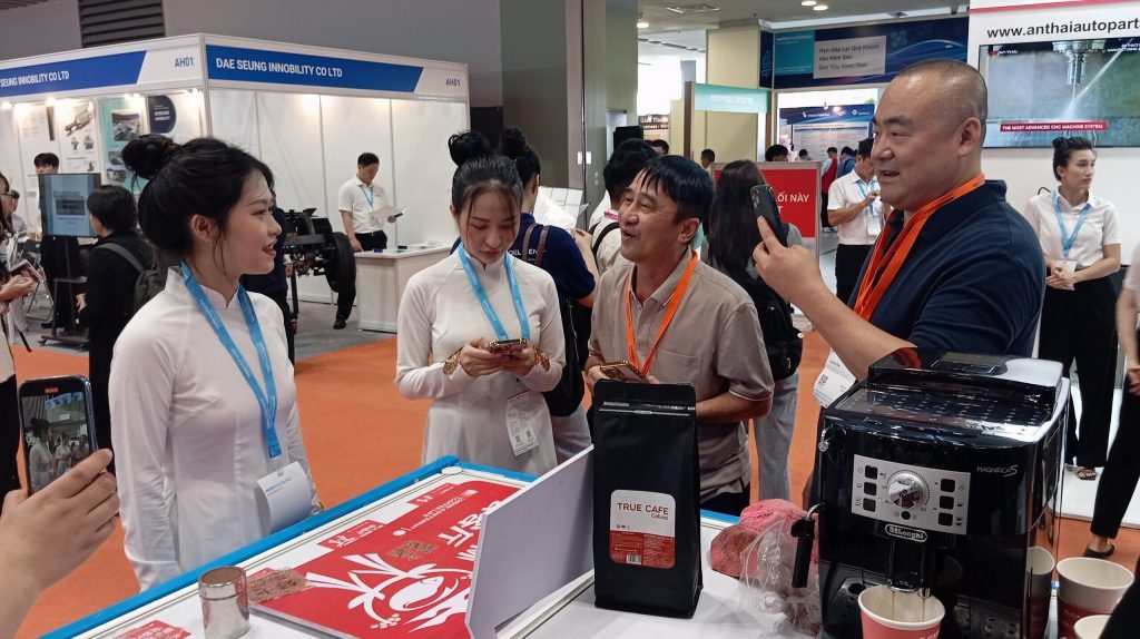 Khách tham quan xem túi cà phê và máy pha tại gian hàng True Cafe trong hội chợ