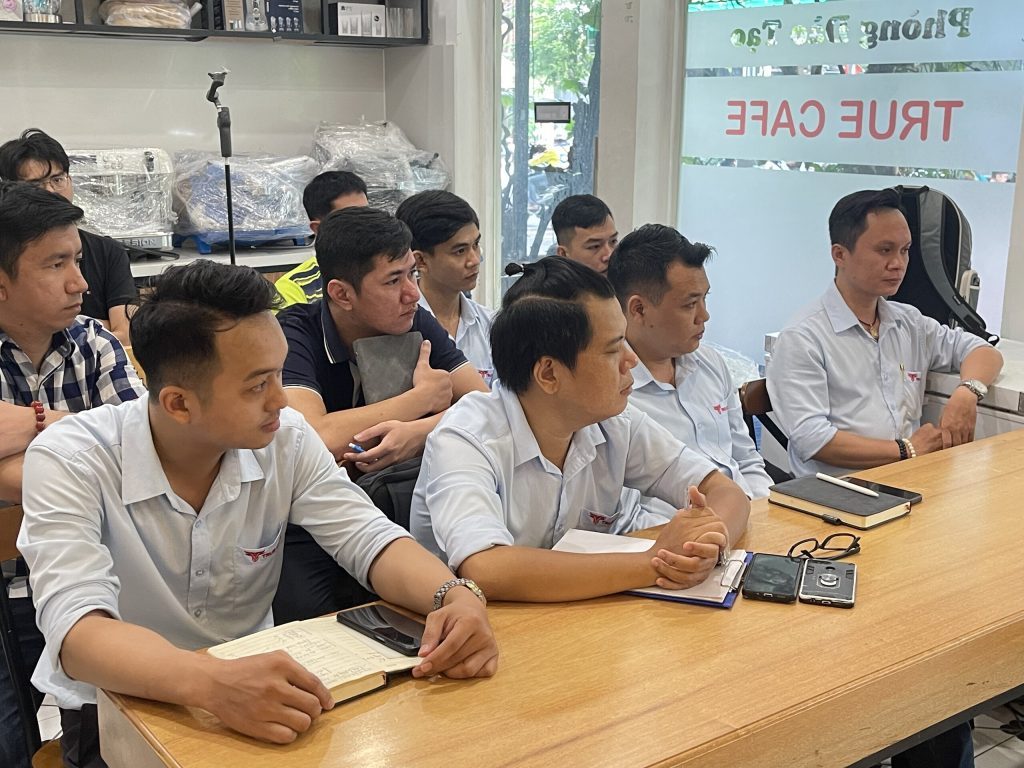 Phòng đào tạo True Cafe với vách kính in tên thương hiệu và học viên ngồi bàn dài