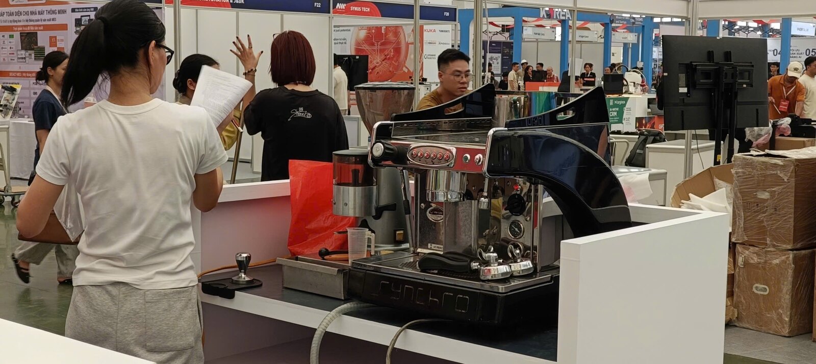 Cận cảnh máy pha espresso và cối xay đang vận hành tại quầy cà phê trong triển lãm