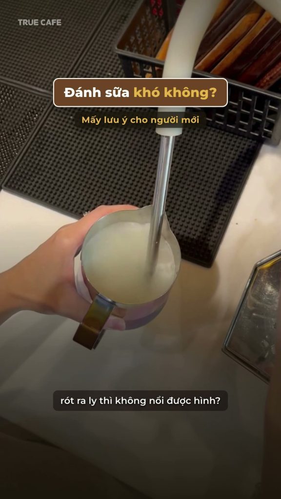 Cận cảnh vòi hơi máy pha đang đánh sữa trong ca inox trên quầy bar
